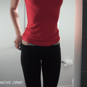 woman wearing pink shirt and black yoga pants before she starts peeing in a jar